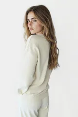 Buzo color crudo con estampado de texto en azul y violeta. Corte holgado y mangas largas.