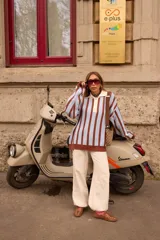 Buzo tejido de punto con diseño a rayas verticales en color celeste y marrón chocolate. Presenta un cuello polo con solapa en color crema y cierre frontal de tres botones, mangas largas de corte holgado y terminaciones en tejido acanalado.