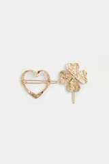 Set de dos hebillas para el pelo metálicas doradas, con textura martillada. Una tiene forma de corazón y la otra de trébol de cuatro hojas.