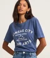 Remera azul de algodón con cuello redondo y mangas cortas. Estampado frontal con la leyenda "Kansas City Original Works House of Arts & Culture Fine Arts" en letras blancas.