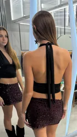 Top halter negro con escote en V profundo y fruncidos laterales con tiras ajustables.