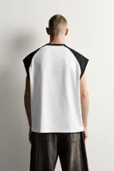 Musculosa relaxed fit de color blanco con hombros y cuello negro estilo color block, cuello redondo y diseño sin mangas con corte sisa.