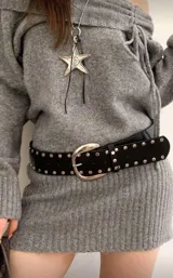 Cinto de cuero sintético negro con tachas metálicas circulares en todo su largo y hebilla metálica plateada de diseño redondeado.