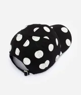 Gorra de sarga de algodón con visera curva, ojales bordados y estampado de lunares, con cierre posterior ajustable con hebilla metálica.
