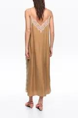Vestido midi de corte recto color marrón, confeccionado en mezcla de lyocell y viscosa. Presenta cierre frontal con botones forrados, escote en V pronunciado con tirantes finos y detalles de encaje en el escote y los laterales.