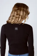 Top negro de tejido de punto acanalado con mangas largas y cierre frontal con botones decorativos.