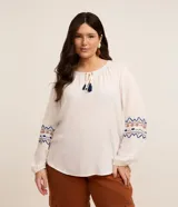 Blusa bata femenina de viscosa color blanco, con cuello redondo con lazo y borlas, manga larga con ajuste en el puño y estampa étnica en los puños.