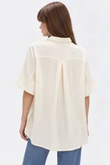 Camisa de viscosa color natural, de corte holgado, con cuello camisero, mangas cortas y cierre frontal con botones.