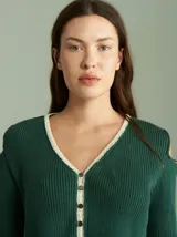 Saco de punto acanalado color bordó con detalles en color crudo en el cuello, plaqueta de botones y ruedo. Presenta aberturas en los hombros y cierre frontal con botones pequeños.