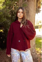 Saco de punto acanalado color bordó, con solapas anchas, cierre frontal cruzado con dos botones y mangas largas de corte holgado.
