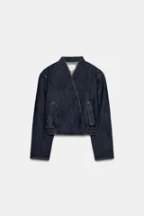 Cazadora bomber de denim color azul oscuro, con escote en pico, cierre frontal cruzado con botones a presión y bajo elástico en los laterales. Cuenta con mangas largas y bolsillos de vivo.