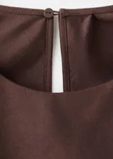 Vestido midi cruzado de color marrón, confeccionado en mezcla de lino y algodón, con cuello redondo, sin mangas y lazo ajustable en la cintura.