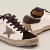 Zapatillas urbanas blancas de cuero vacuno, con puntera y talón en gamuza negra, aplique de estrella en cuero color aluminio y cordones negros encerados.