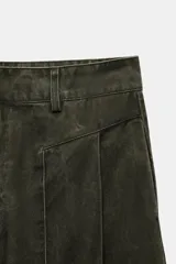 Pantalón verde militar de tiro medio, con bolsillos delanteros, pliegues y tejido con efecto lavado. Cuenta con cierre frontal con cremallera y gancho metálico.