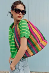 Bolso tipo tote bag confeccionado en yute 100%, con diseño de rayas verticales multicolor de textura esponjosa y asa de mano revestida en fibra natural. Cuenta con cierre de imán.