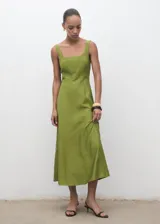 Vestido midi de corte evasé en color verde oliva. Presenta tirantes anchos, escote cuadrado y costuras decorativas verticales que estilizan la silueta. Incluye cierre de cremallera en la parte posterior y forro interior.