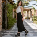 Botín de cuero vacuno color marrón oscuro, con taco de madera foliado en cuero de 5cm de altura, cierre lateral interno y horma de punta fina.