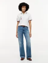 Chomba de corte regular confeccionada en algodón elástico, con cuello polo y cartera de dos botones. Presenta ribetes distintivos en cuello y puños, cinta lateral y múltiples logos bordados que incluyen Tommy Hilfiger, Cadillac Formula 1 Team y Pirelli.