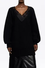 Jersey largo de punto negro con escote en V profundo adornado con detalles de encaje. Presenta mangas largas con puños ajustados y un diseño de tejido acanalado.