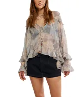 Blusa de chiffon con estampado floral en tonos pastel y grisáceos. Presenta escote en V con cierre frontal de botones nacarados, mangas largas amplias con puños con volados y un ruedo con volado en el bajo.