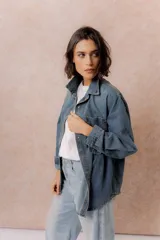 Camisa de denim de lavado medio con calce oversize, cuello camisero, cierre frontal con botones y bolsillos aplicados en el frente.