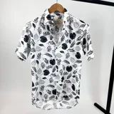 Camisa blanca con estampado de hojas en negro, de manga corta y cuello italiano.