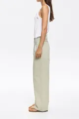 Pantalón vaquero de corte wide leg en color verde claro. Presenta un diseño de tiro medio con cierre frontal de botón y cremallera, además de cinco bolsillos clásicos.