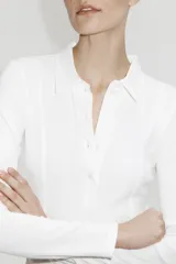 Remera polo de manga larga confeccionada en punto de algodón, con cuello clásico, tapeta frontal con botones y costuras moldeadoras en el frente.
