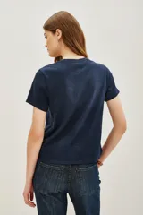 Remera azul marino de algodón con cuello redondo y mangas cortas. Presenta la frase 'LONDON LOVERS' bordada en el frente con cuentas metálicas.