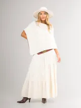 Poncho de corte holgado y diseño minimalista, confeccionado en tejido liviano de color beige, con cuello redondo y caída fluida.