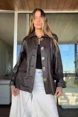 Tapado de cuero ovino color chocolate con detalles de pasamanería y presillas en gamuza al tono. Presenta cierre frontal con botones grandes y mangas largas con puños ajustados.