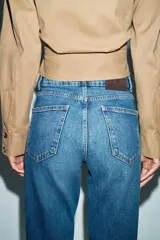 Jeans de tiro alto con corte mom fit, diseño de cinco bolsillos y raya planchada frontal. Presenta cierre frontal con cremallera y botón.