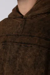 Buzo canguro oversize con efecto lavado desgastado, confeccionado en friza pesada. Presenta diseño con recortes, capucha amplia y puños y ruedo acanalados.