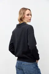 Sweater de punto color gris oscuro, con cuello polo y cierre frontal parcial con botones. Presenta mangas largas y un diseño de calce holgado.