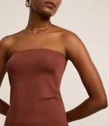 Blusa marrón sin breteles, de corte ajustado y bajo asimétrico, con textura acanalada y laterales fruncidos.