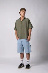 Camisa de manga corta de color verde militar, confeccionada en una mezcla de lino y viscosa. Posee un calce regular, cuello plano y cierre frontal con botones, destacándose por su textura liviana y respirable.