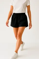 Short negro de poliéster, de calce holgado y tiro medio, con cintura elástica y cordón ajustable.