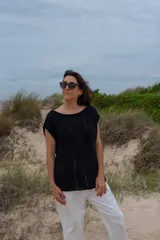 Chaleco negro de alpaca tejido a mano, ligeramente oversize, con hombros anchos, cuello tipo bote, puntos calados en frente y espalda, y tajos laterales en el bajo.