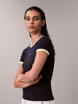 Remera Calvin Klein de corte baby fit y manga corta, confeccionada en tejido acanalado negro. Presenta cuello redondo y puños con ribetes en contraste blanco y amarillo fluo, y el logo de la marca bordado en el pecho.