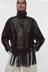 Chaqueta de cuero sintético con textura rugosa, cuello alto con trabilla, cierre frontal con cremallera y botones a presión, bolsillos delanteros y bajo ajustable con hebilla metálica.