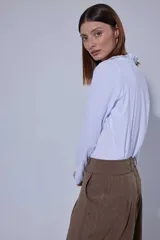 Blusa de estilo romántico con frente de lino y espalda y mangas de algodón con elastano. Presenta un diseño con mini volados en la pechera, cuello redondo y cierre frontal con botones.