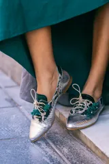 Zapato blucher plateado con estampado animal print, cordones y detalle de flor en el final del cordón. Interior 100% piel y suela de cuero. Incluye plantilla de lana y piel.