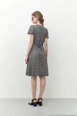 Vestido midi con estampado geométrico en blanco y negro, corte cruzado, mangas cortas y escote en V.