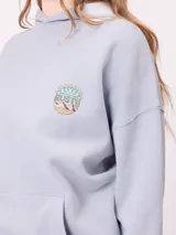 Canguro color crema con capucha y estampado grande en la espalda de un sol con un ojo, montañas, mariposas y texto.