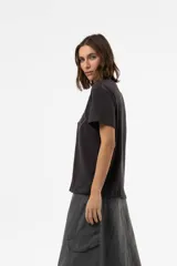 Remera de algodón con calce relajado, color negro lavado, cuello redondo y mangas cortas. Presenta una estampa floral bordada en líneas blancas en el frente.