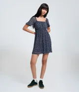 Vestido corto evasê de tule ligero color azul marino con estampado floral liberty fullprint en blanco. Posee escote recto, mangas cortas abullonadas y canesú fruncido en el busto.