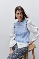 Chaleco de punto calado color celeste con cuello redondo y terminaciones en contraste marrón, de silueta cómoda y diseño sin mangas.