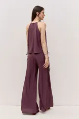 Pantalón de calce amplio y caída suelta, color bordó, con cintura alta y detalle de tiras laterales. Su silueta es oxford.