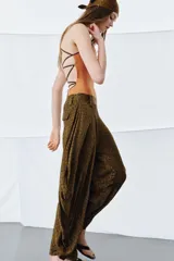 Pantalón de tiro medio confeccionado en viscosa, con diseño de pierna ancha y drapeado lateral. Presenta cintura con trabillas y cierre de cremallera oculto en la costura.