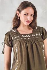 Blusa azul marino de algodón con bordados florales y de animales en blanco. Tiene escote cuadrado, mangas cortas con lazos y corte holgado.